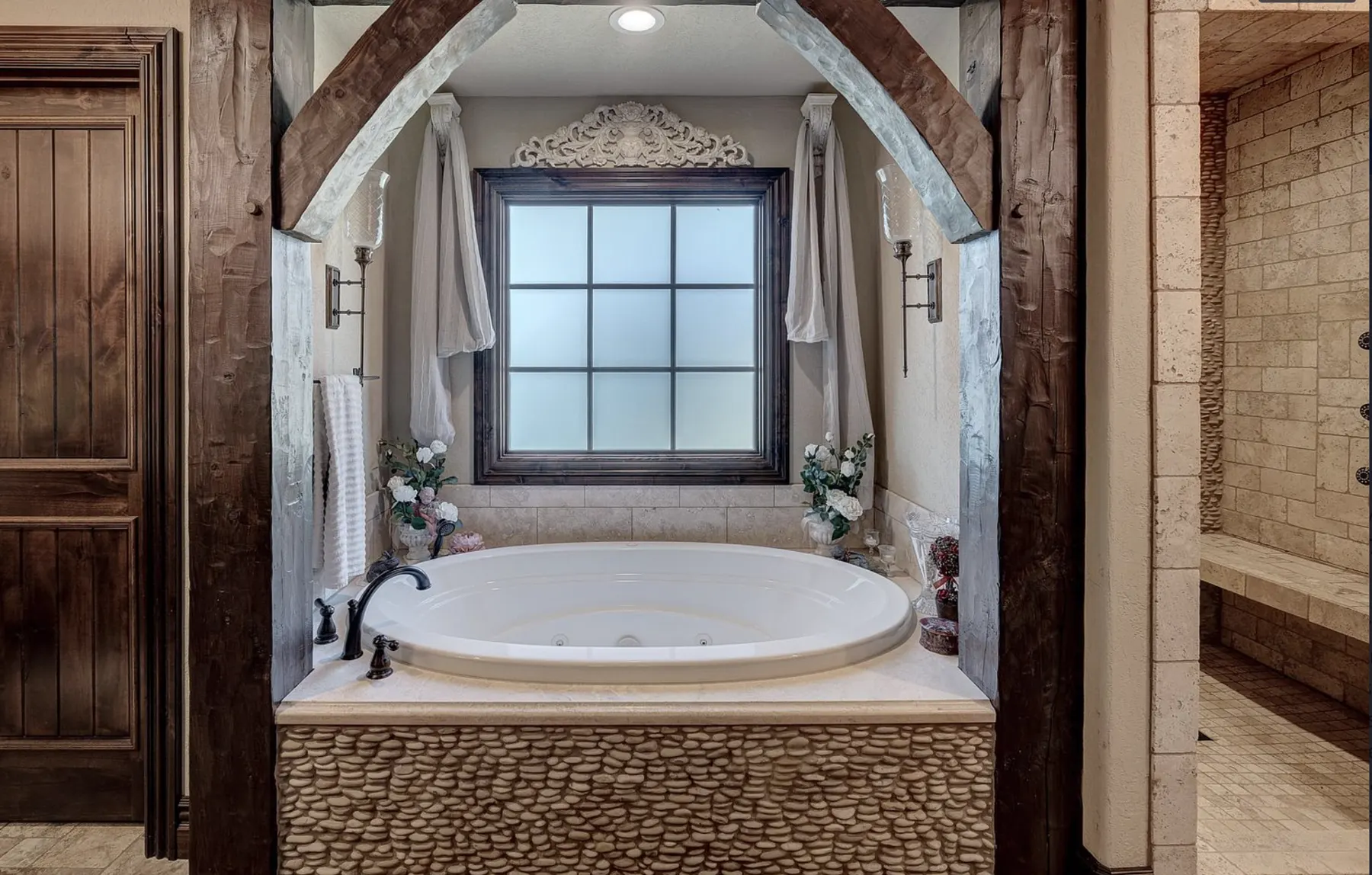 Remodeled bathroom with a soaking tub under a timber arch