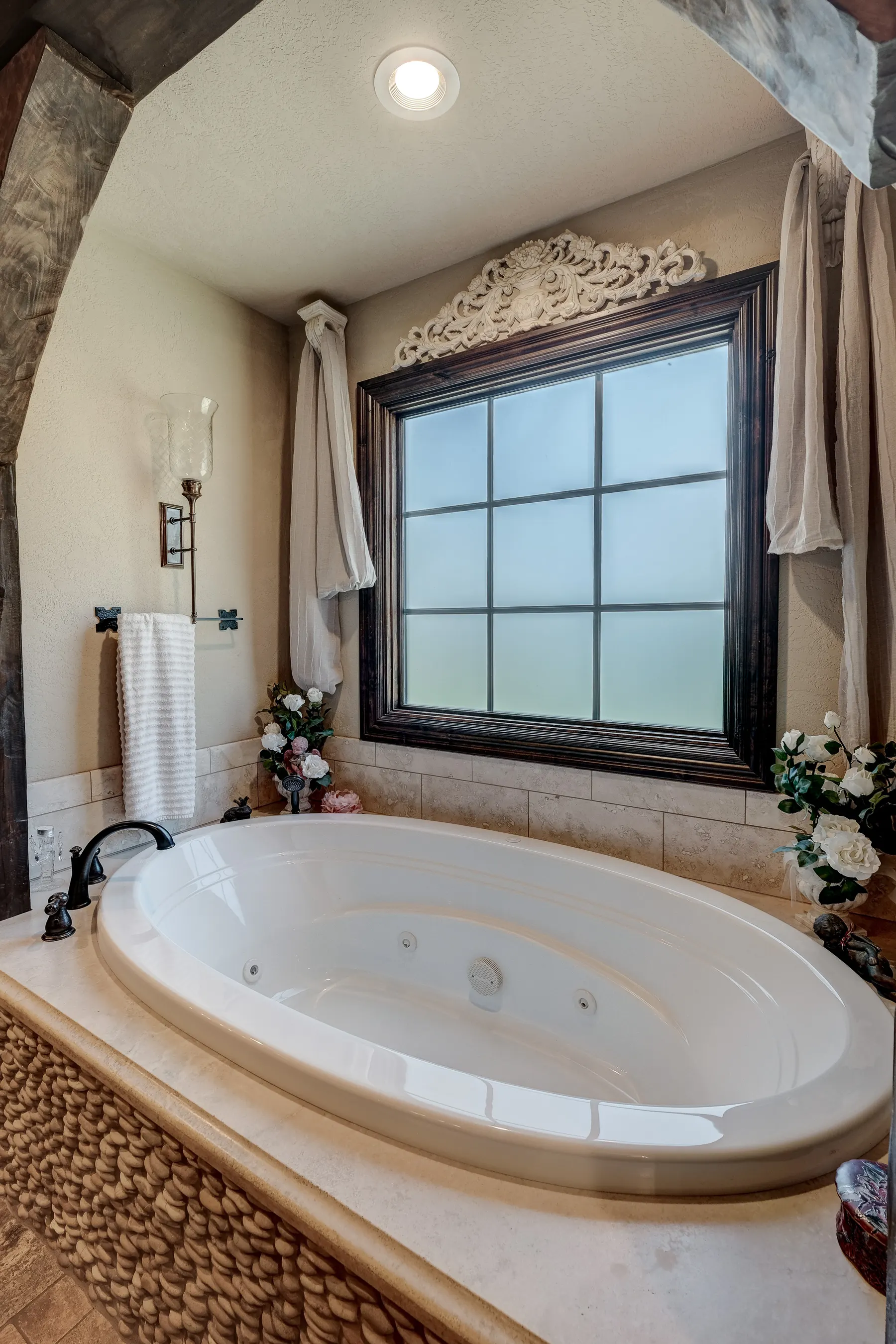 Soaking tub with a stone surround under a window