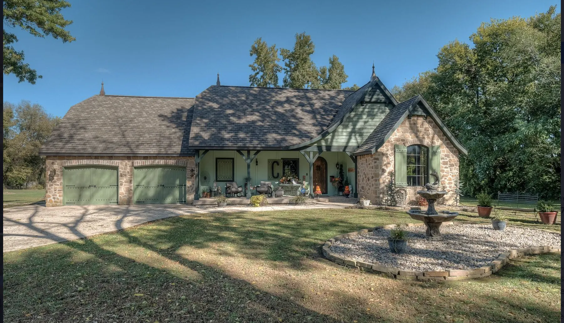 Stone custom home with a fountain and landscaped lawn