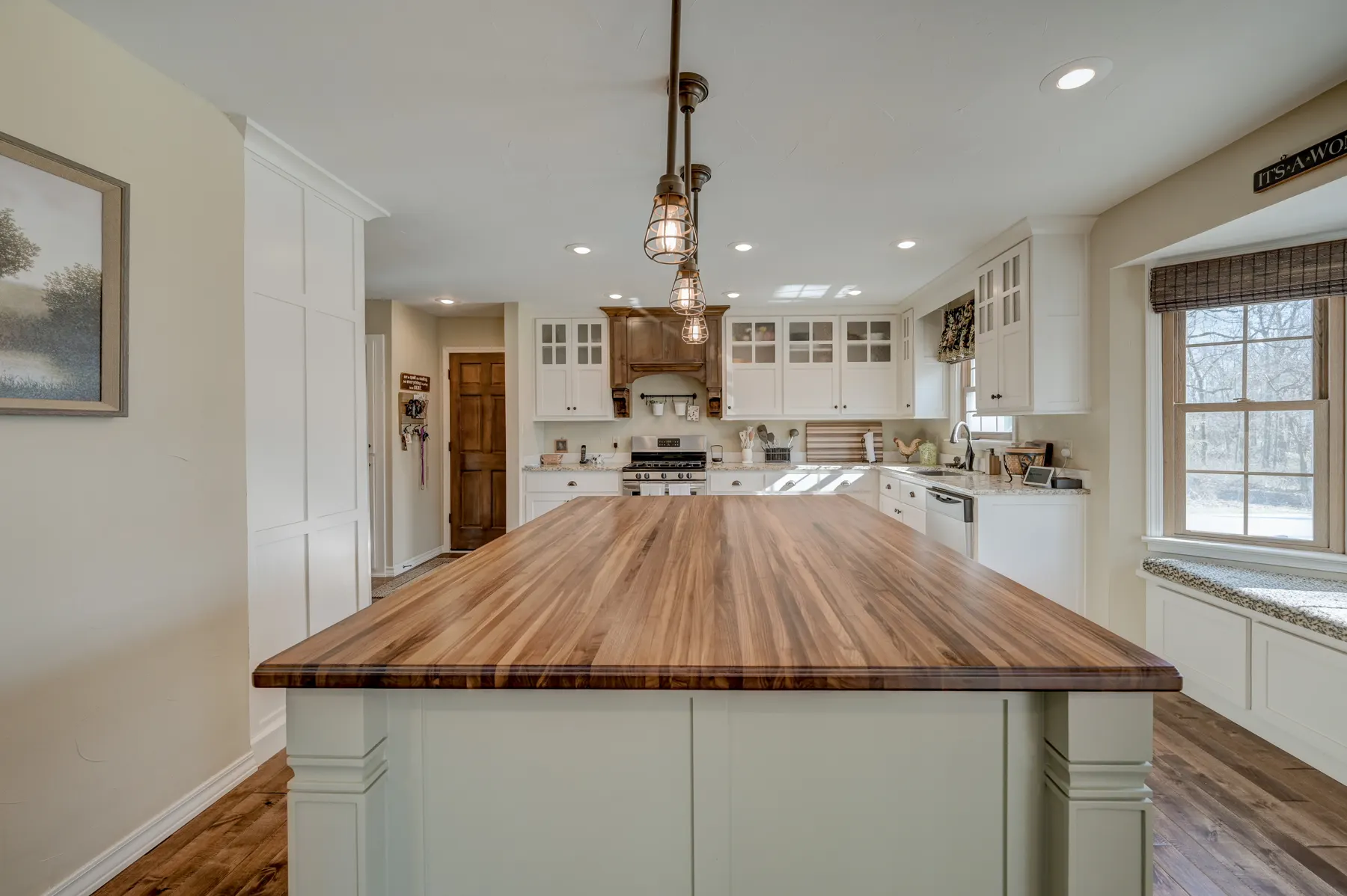 White kitchen with a butcher-block island and pendant lights