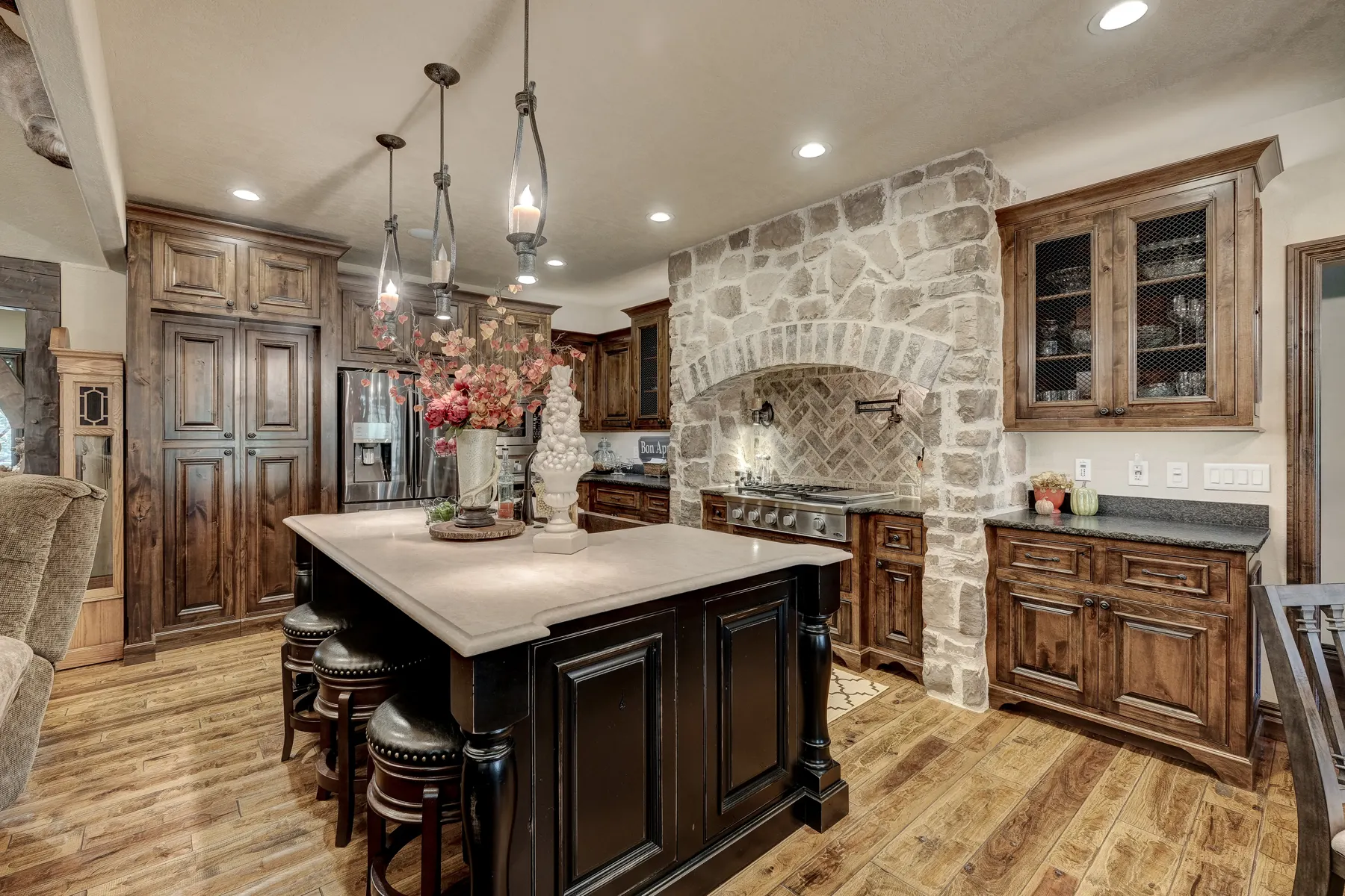 Custom kitchen with a stone archway, dark island and wood cabinetry built by Bates Building Company