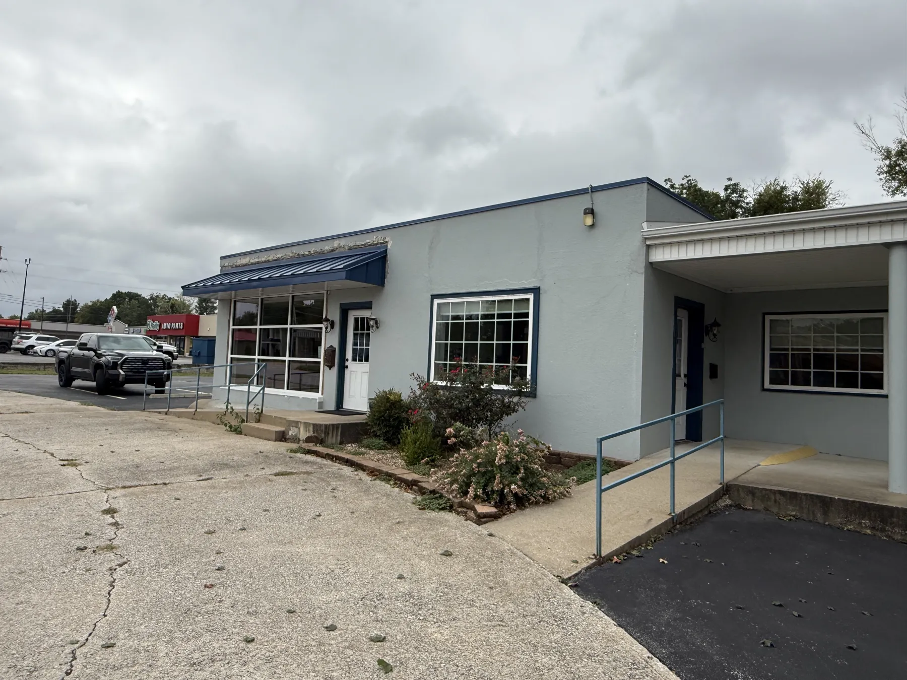 Knell Tax with the new storefront window wall, entry door and blue standing-seam awning installed, before paint