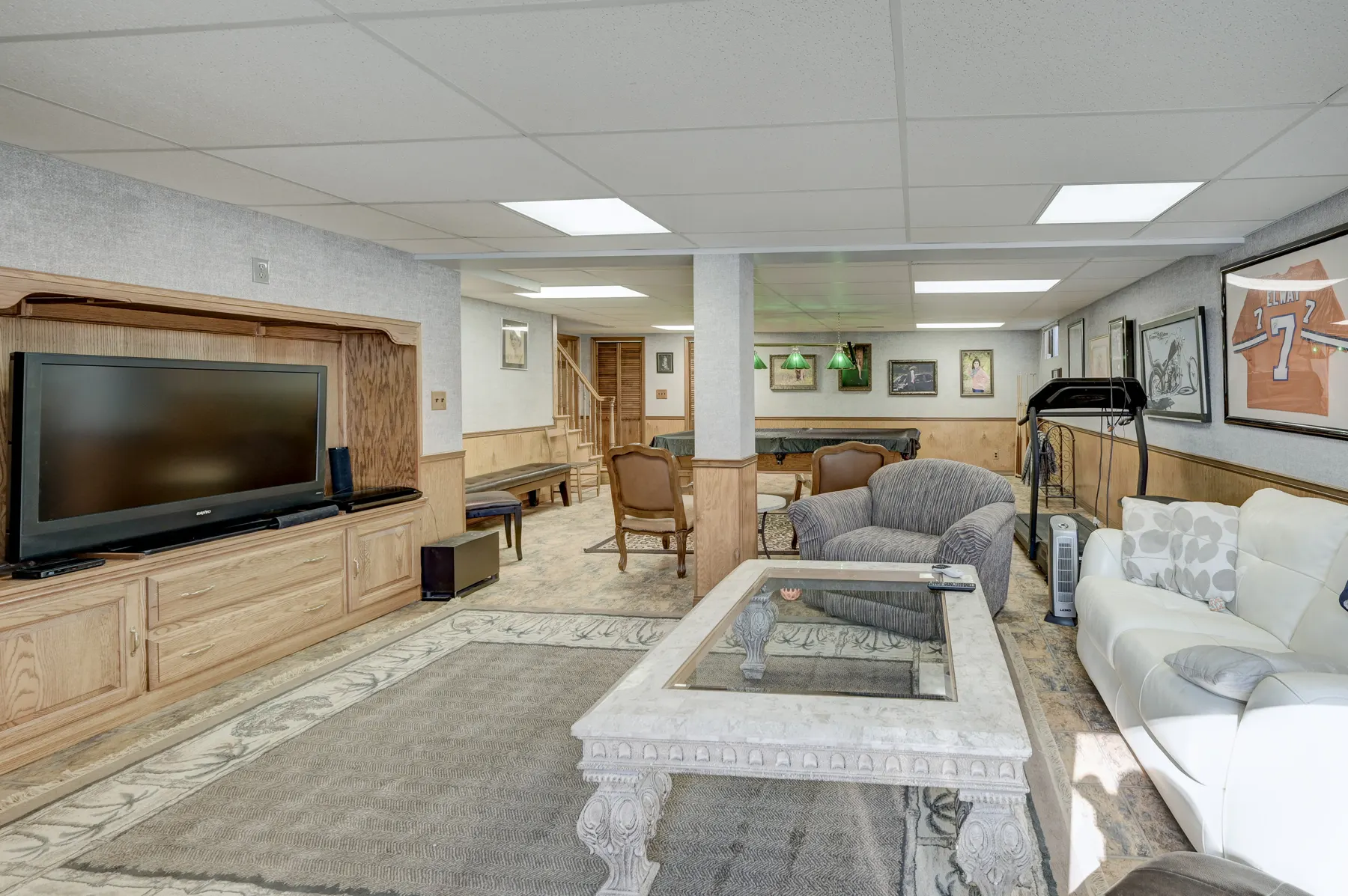 Finished basement living area with a TV wall and sofa