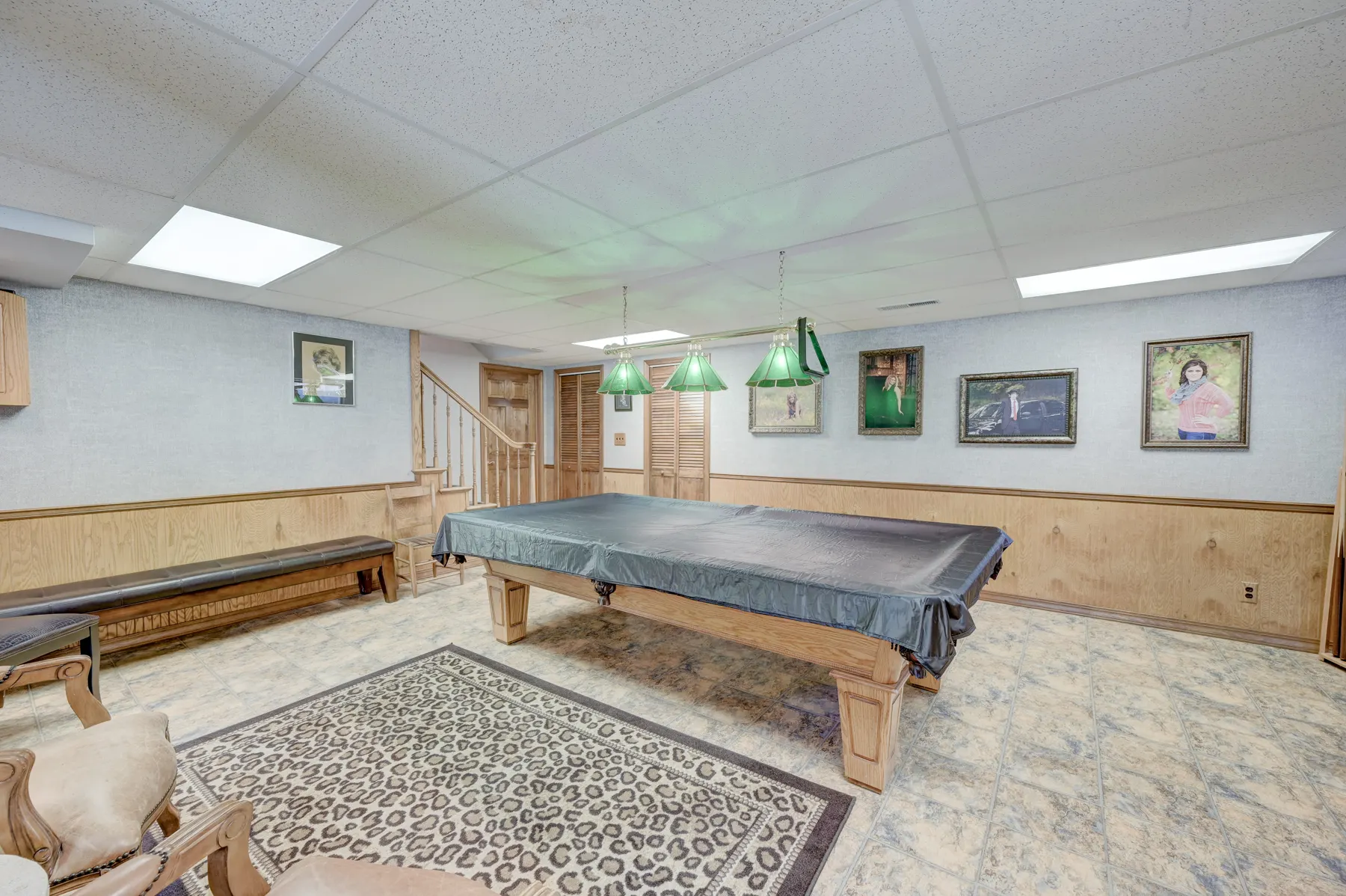 Finished basement with a pool table and wainscoting