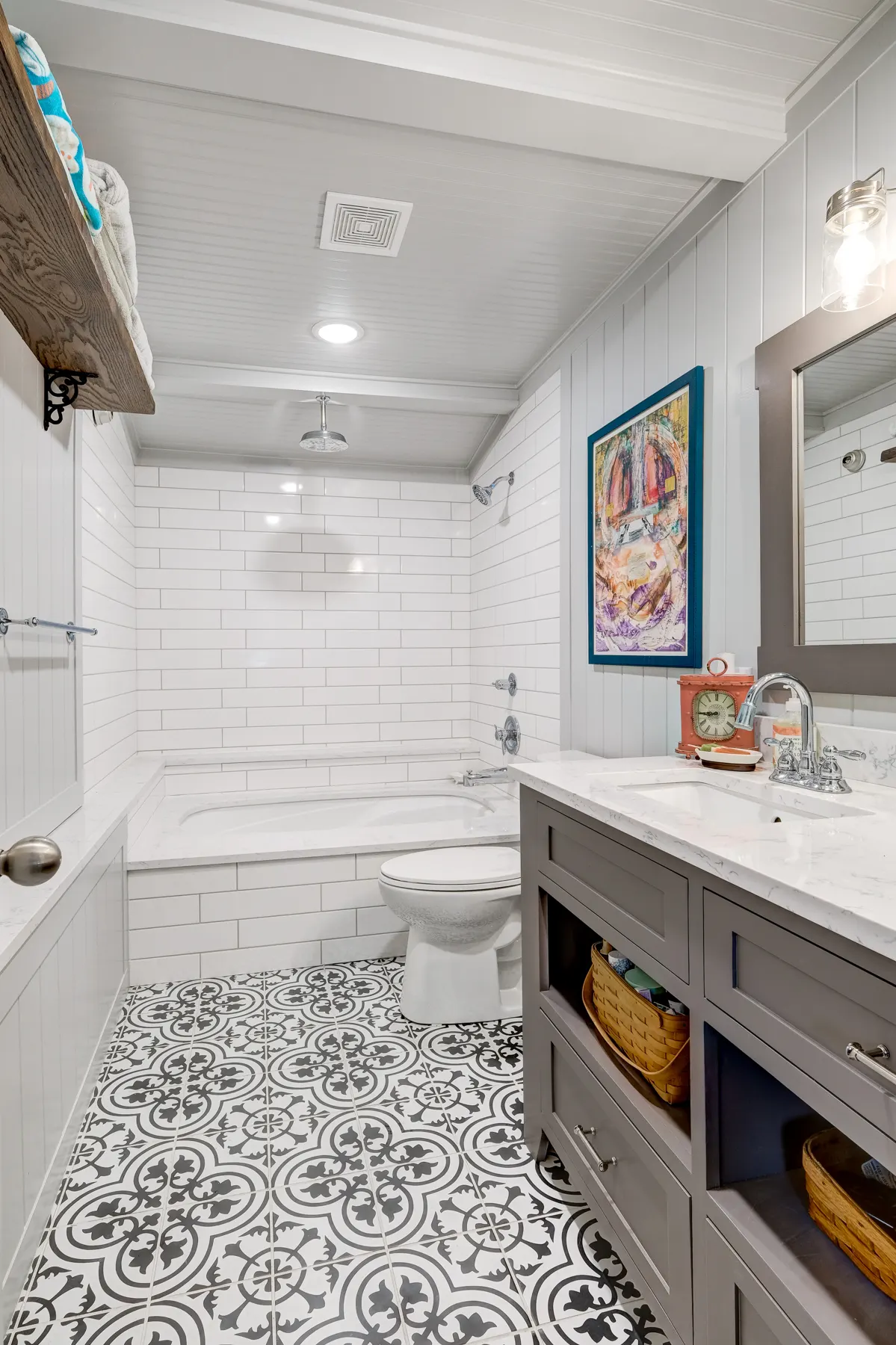 White bathroom with a patterned tile floor and subway tile