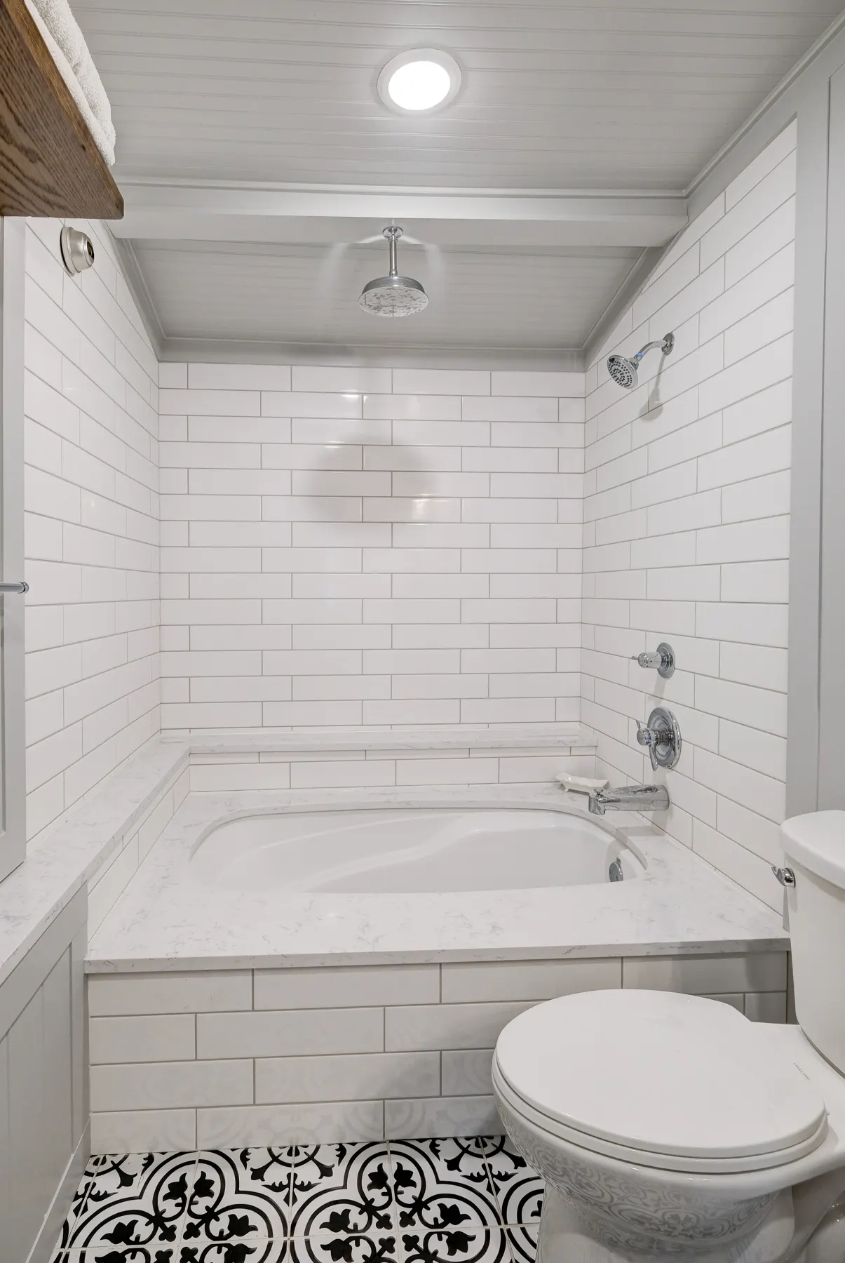 Tub and shower with white subway tile and patterned floor