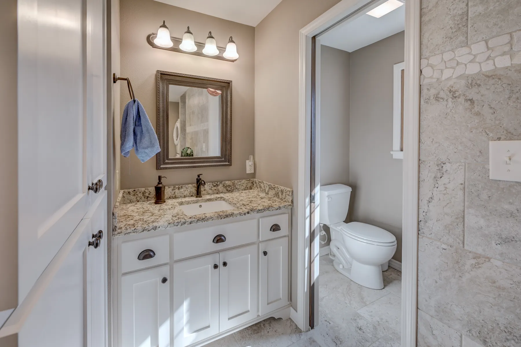 Bathroom with a white vanity, granite top and tile shower