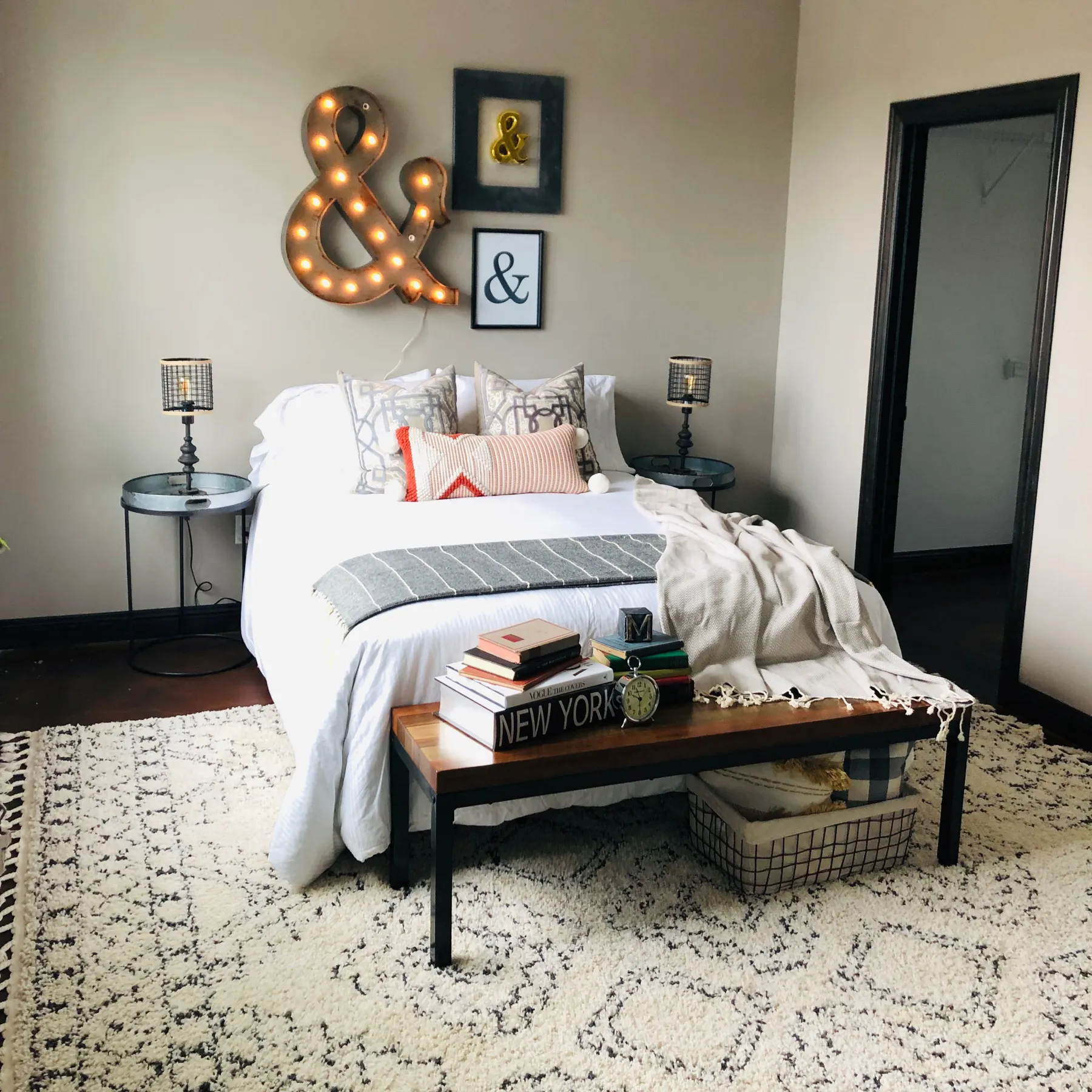 Bedroom with a black iron bed, patterned rug and a wood bench at the foot of the bed