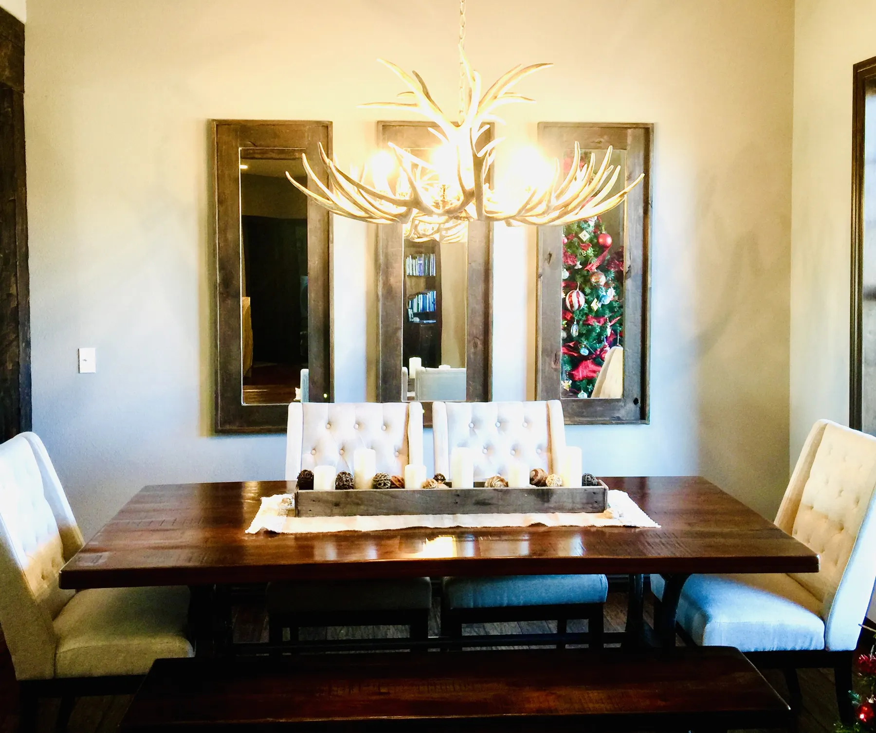 Dining room with an antler chandelier and a tall upholstered bench