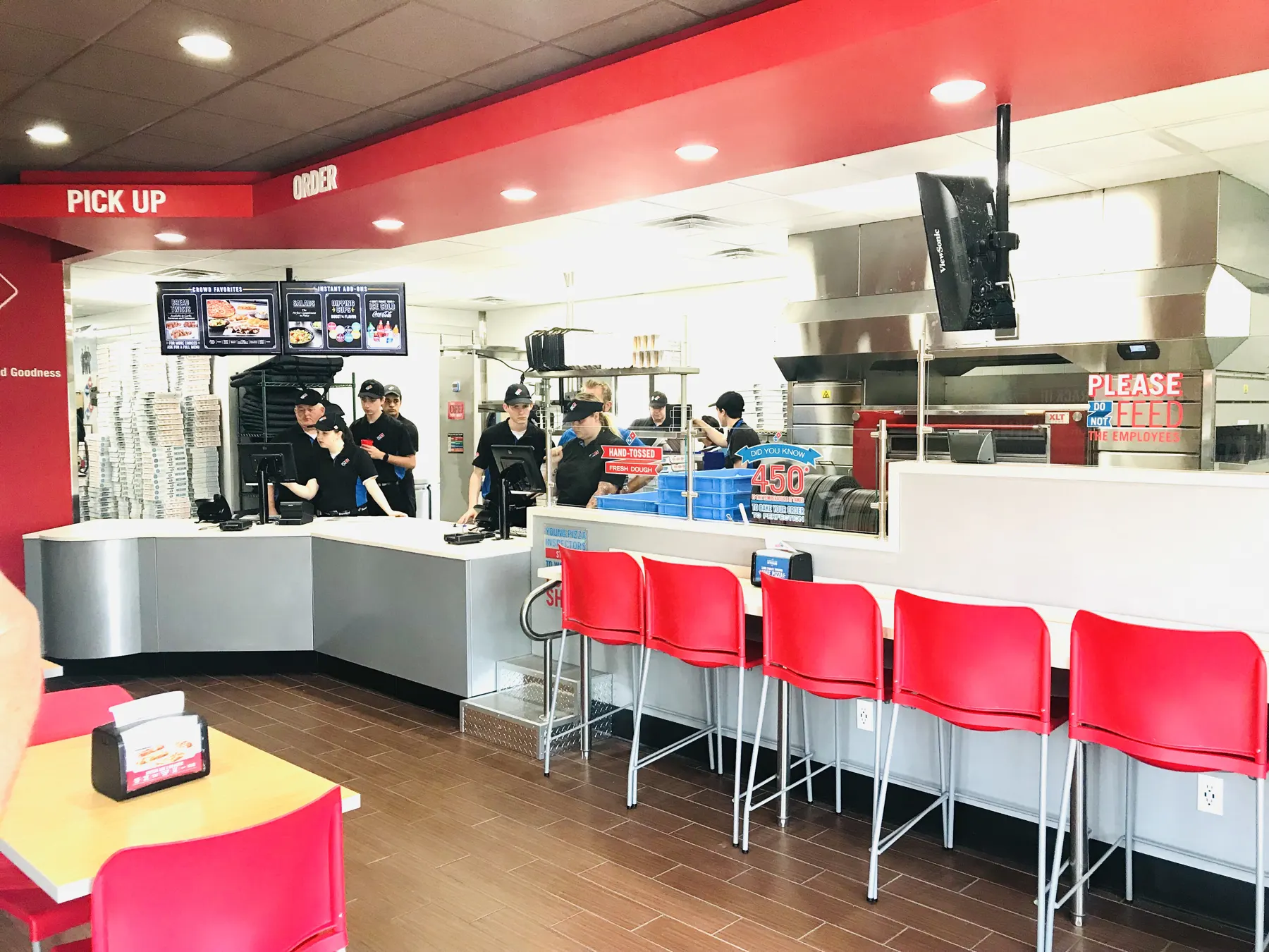 Domino's pickup area with red stools and an open make line