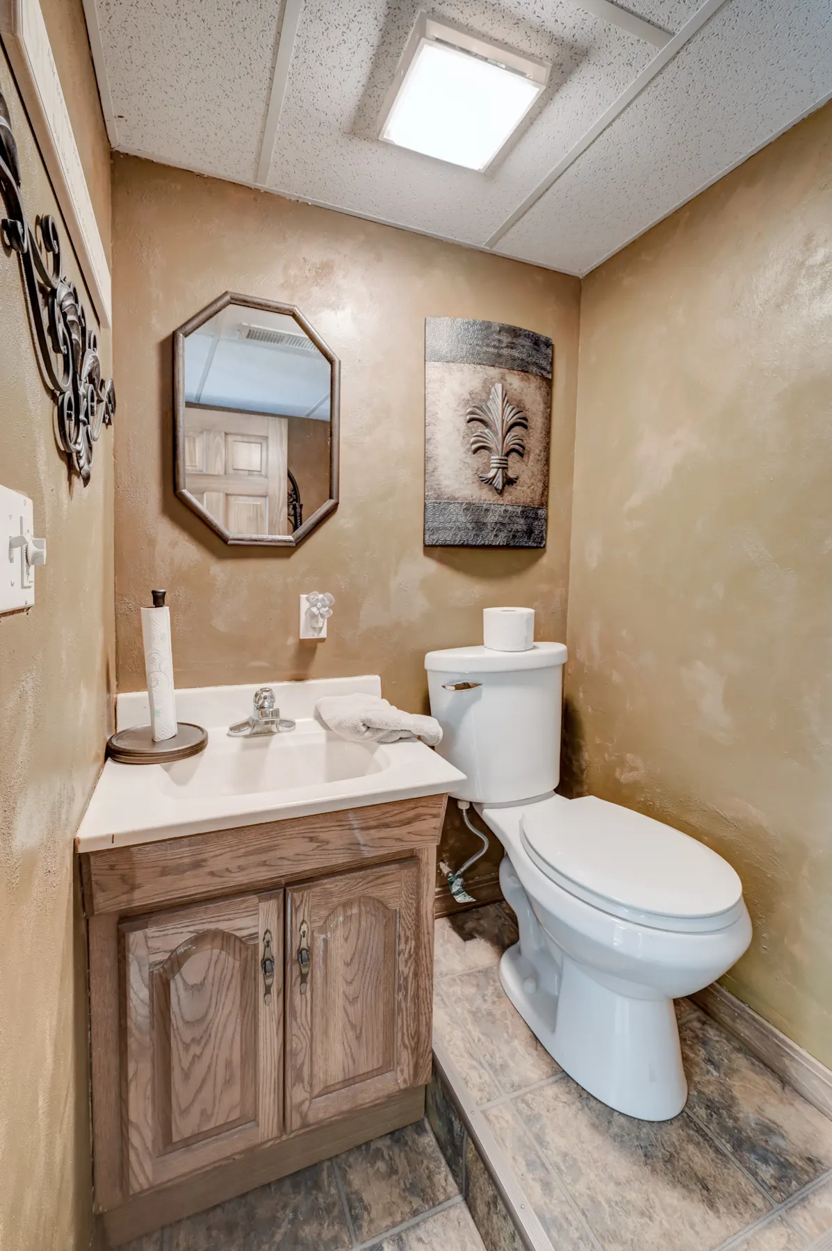 Half bath with a wood vanity and octagon mirror
