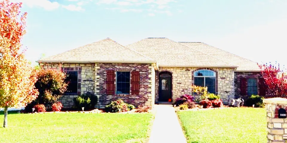 Brick and stone home with flower beds and a front walk