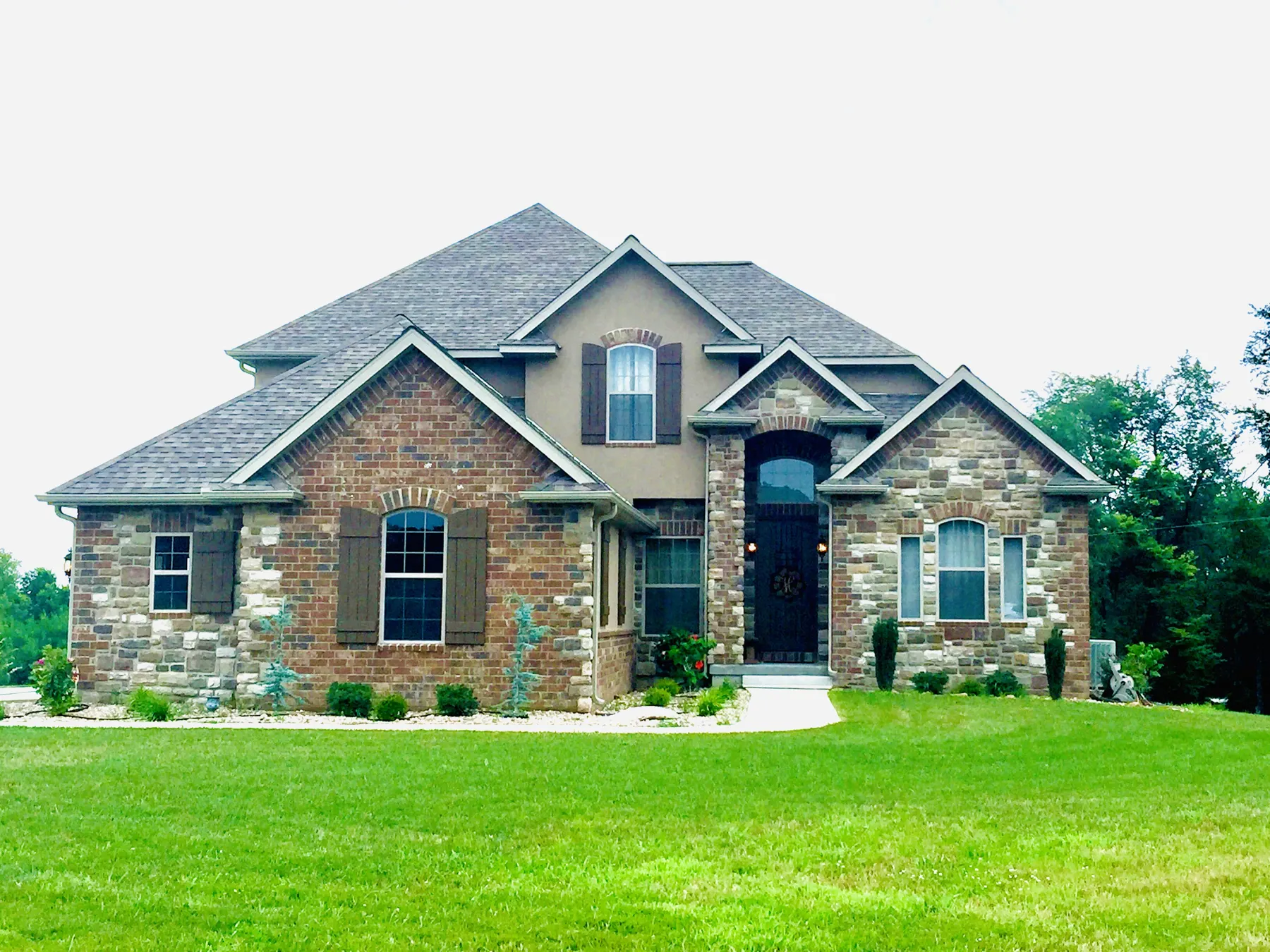 Two-story custom home with stone and brick and a manicured front lawn