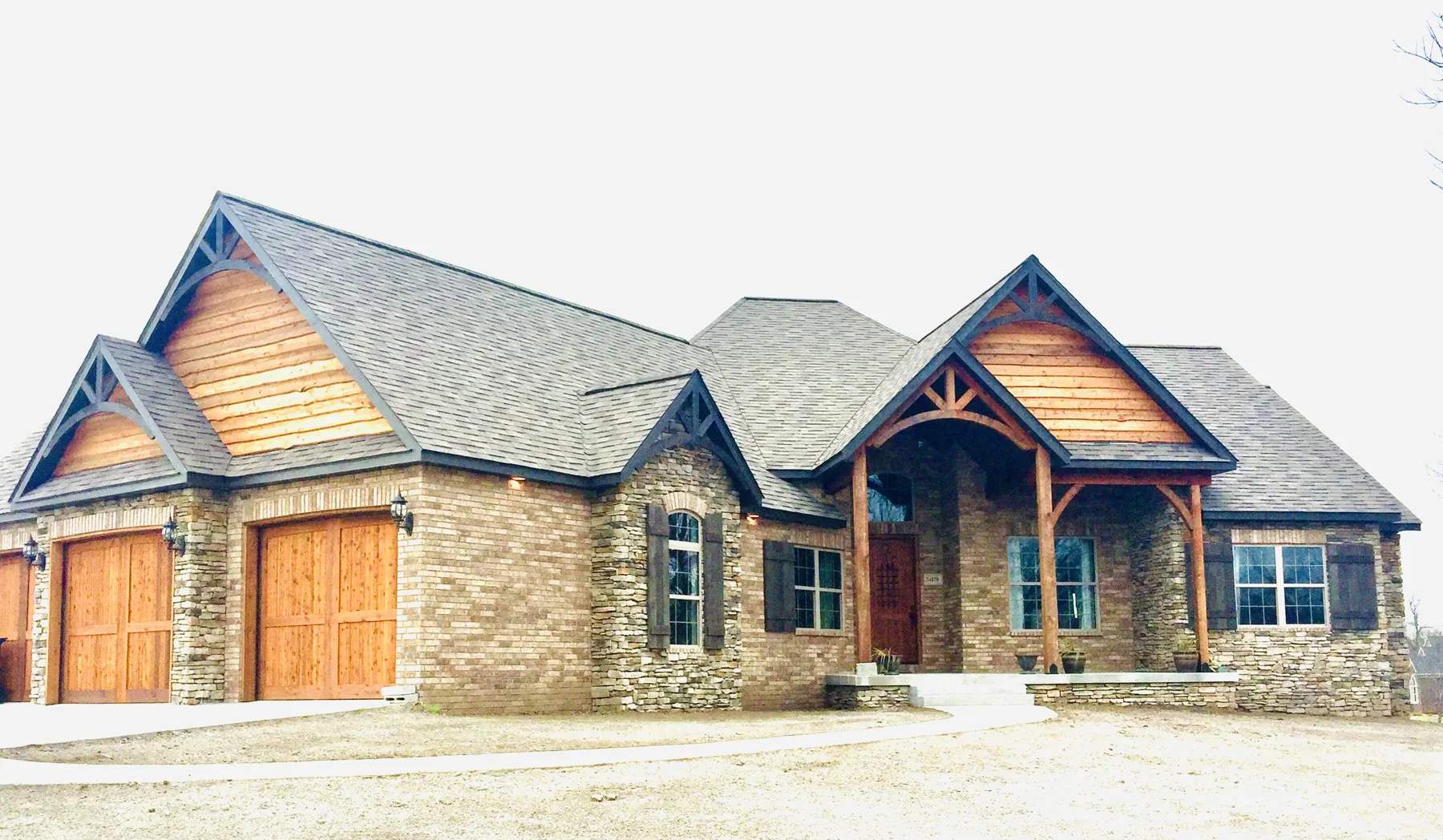 Custom home with stone, cedar shake gables and a timber-framed entry