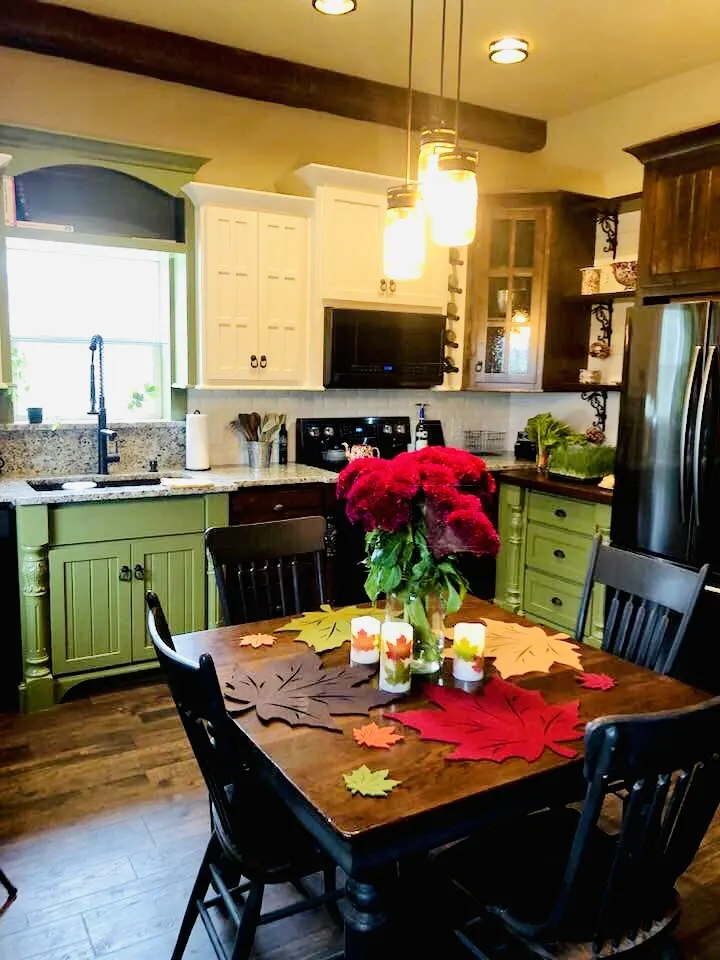 Green kitchen and dining area with a dark wood table
