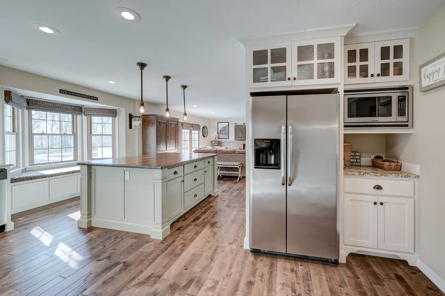 White kitchen with glass-front uppers, stainless refrigerator and island