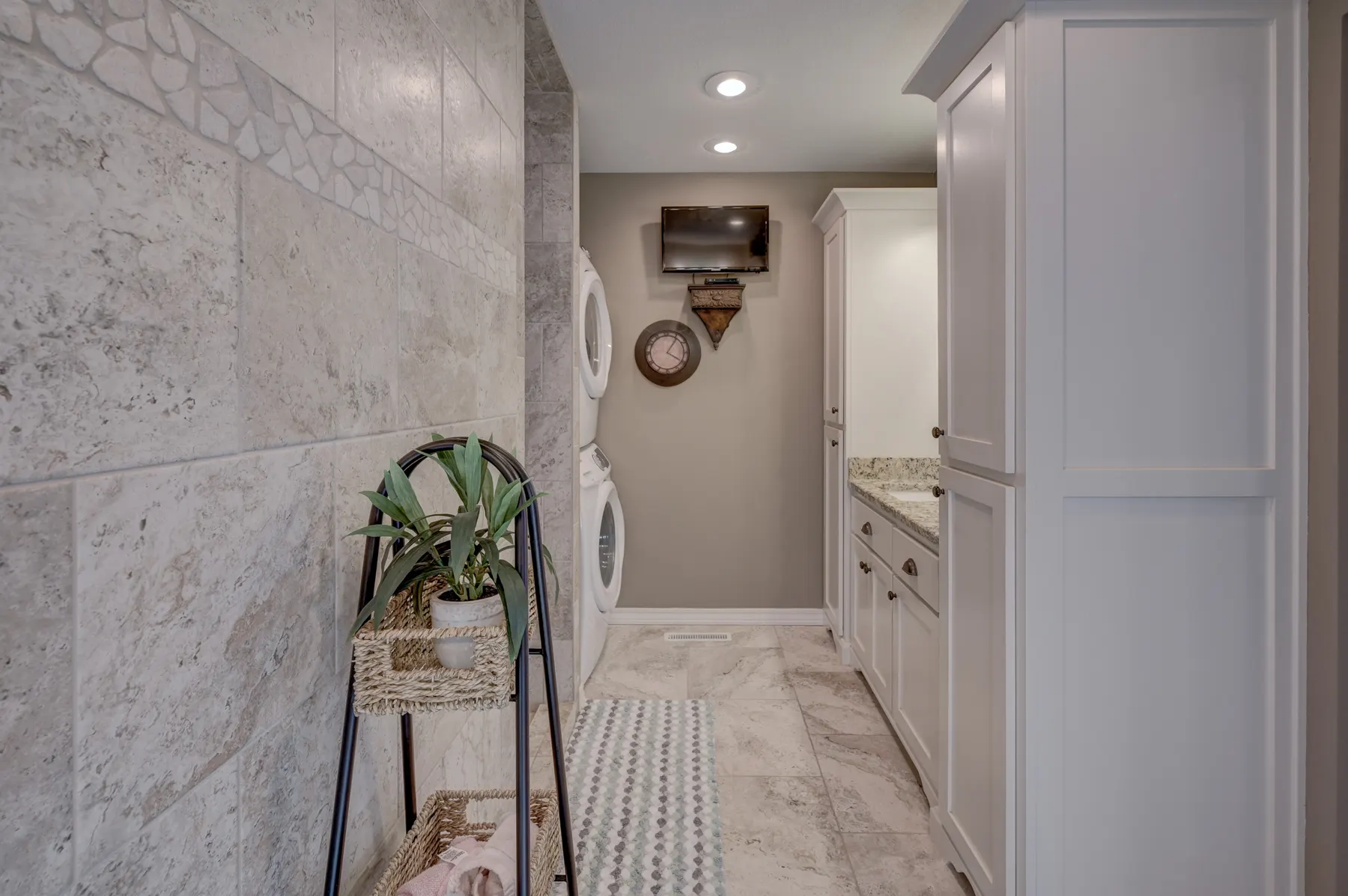 Laundry hall with white cabinets and marble-look tile