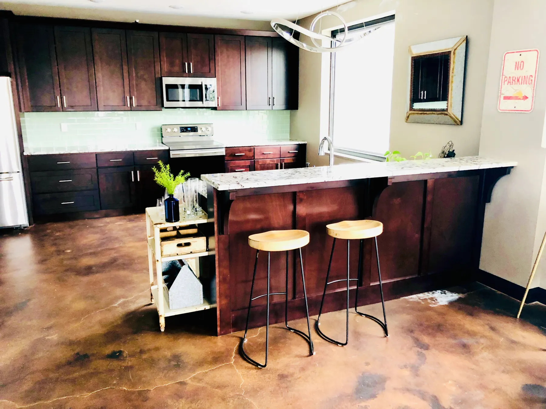 Loft kitchen with dark cabinets, a bar and stained concrete floors