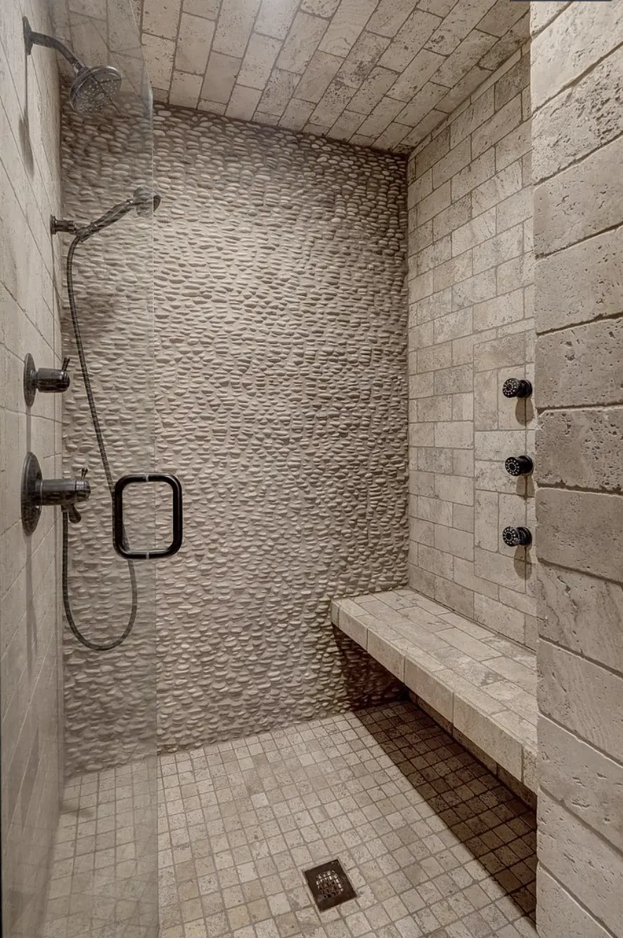 Walk-in tile shower with a stacked stone wall and bench