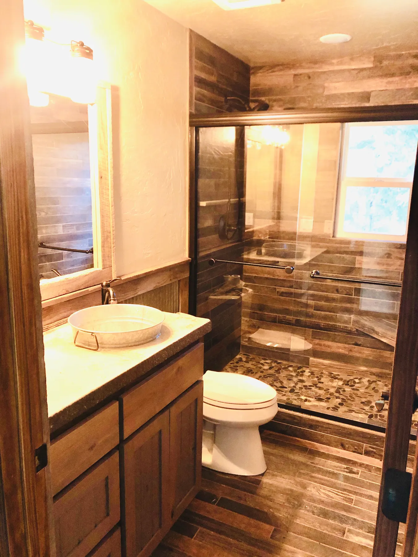 Bathroom with a vanity, toilet and pebble-floor shower