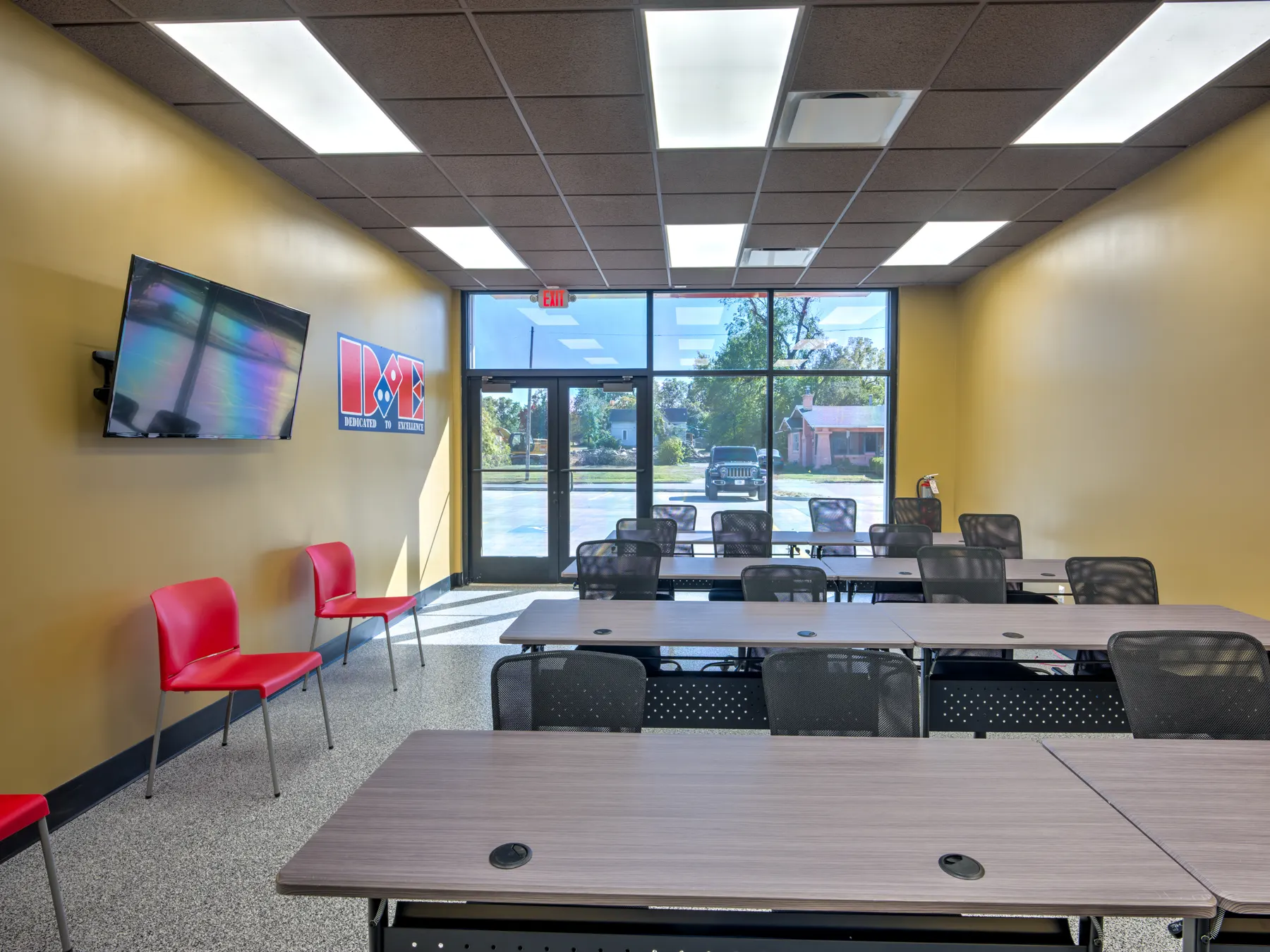 Training room with yellow walls, wall-mounted TV and rows of tables