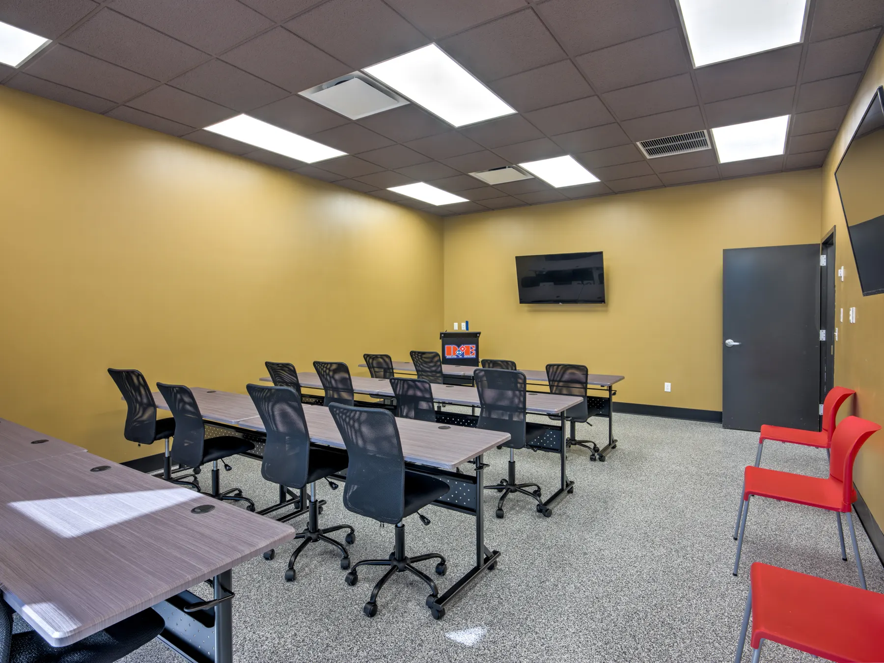 Training room seen from the front with tables and red chairs
