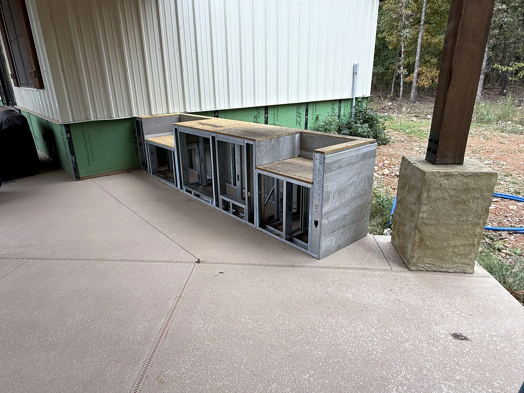 Outdoor kitchen cabinet frames being built under the pavilion next to a stone column base