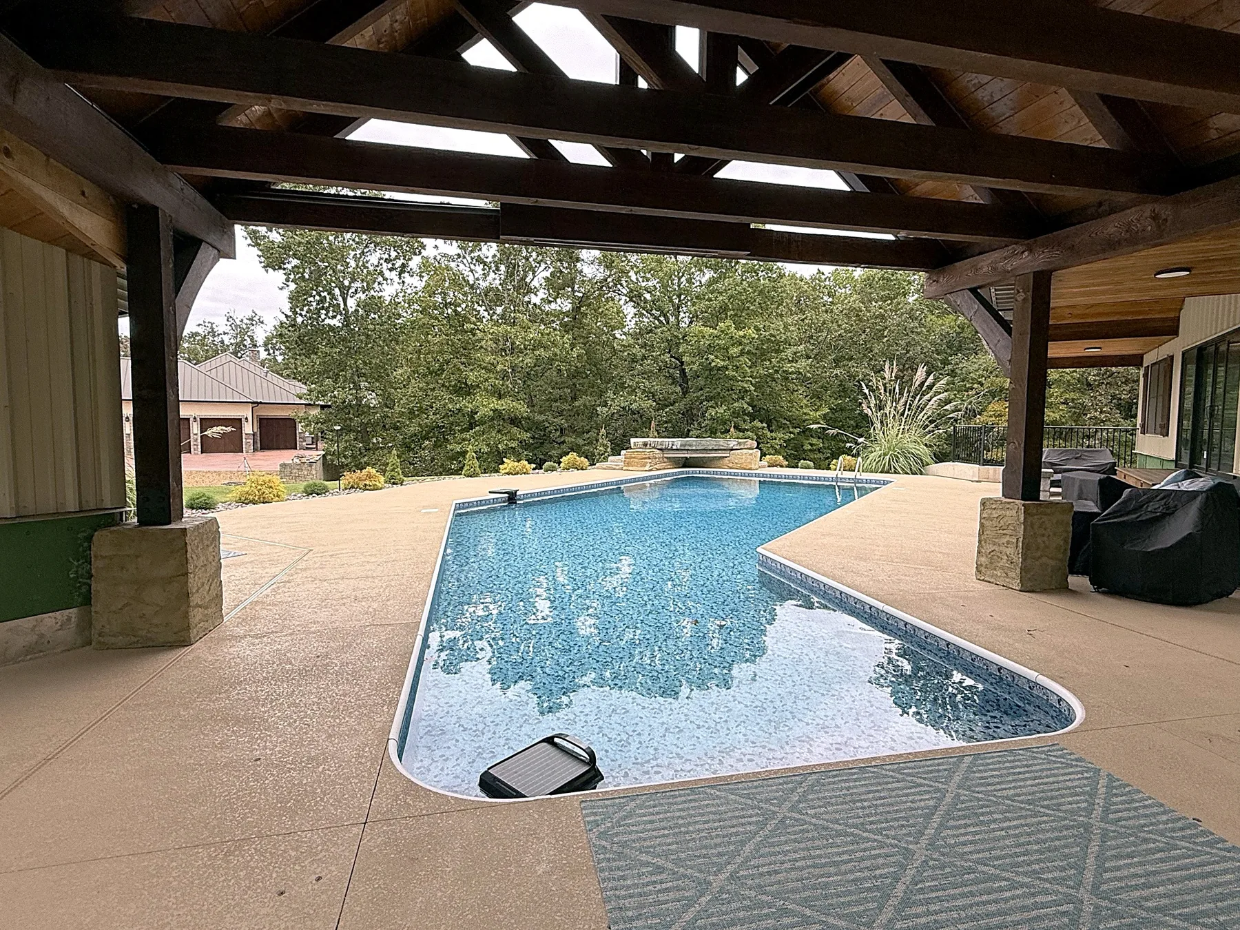 View of the pool and deck from under the timber-framed pavilion