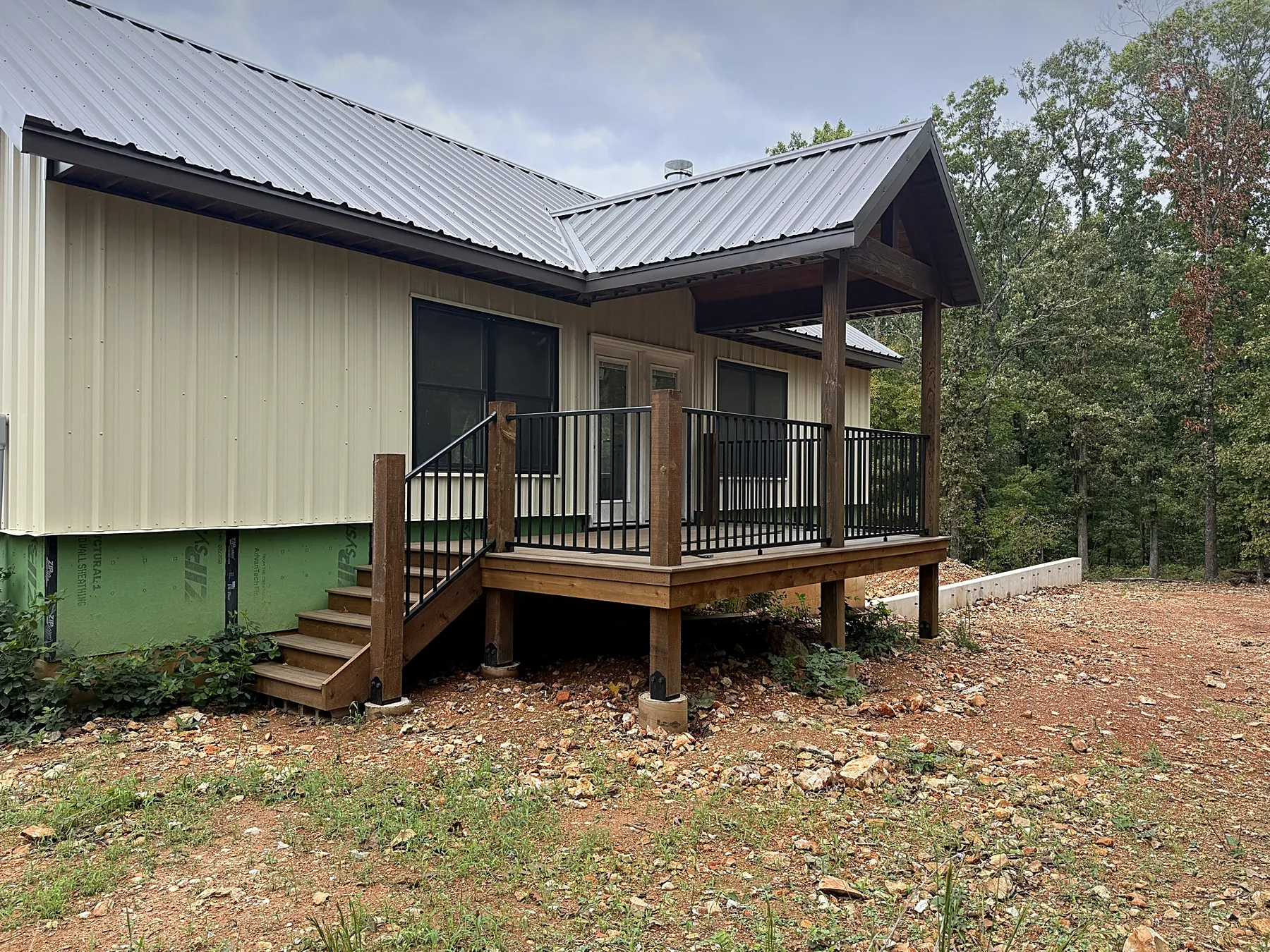 Pool house side porch and stained wood deck with new black metal railing