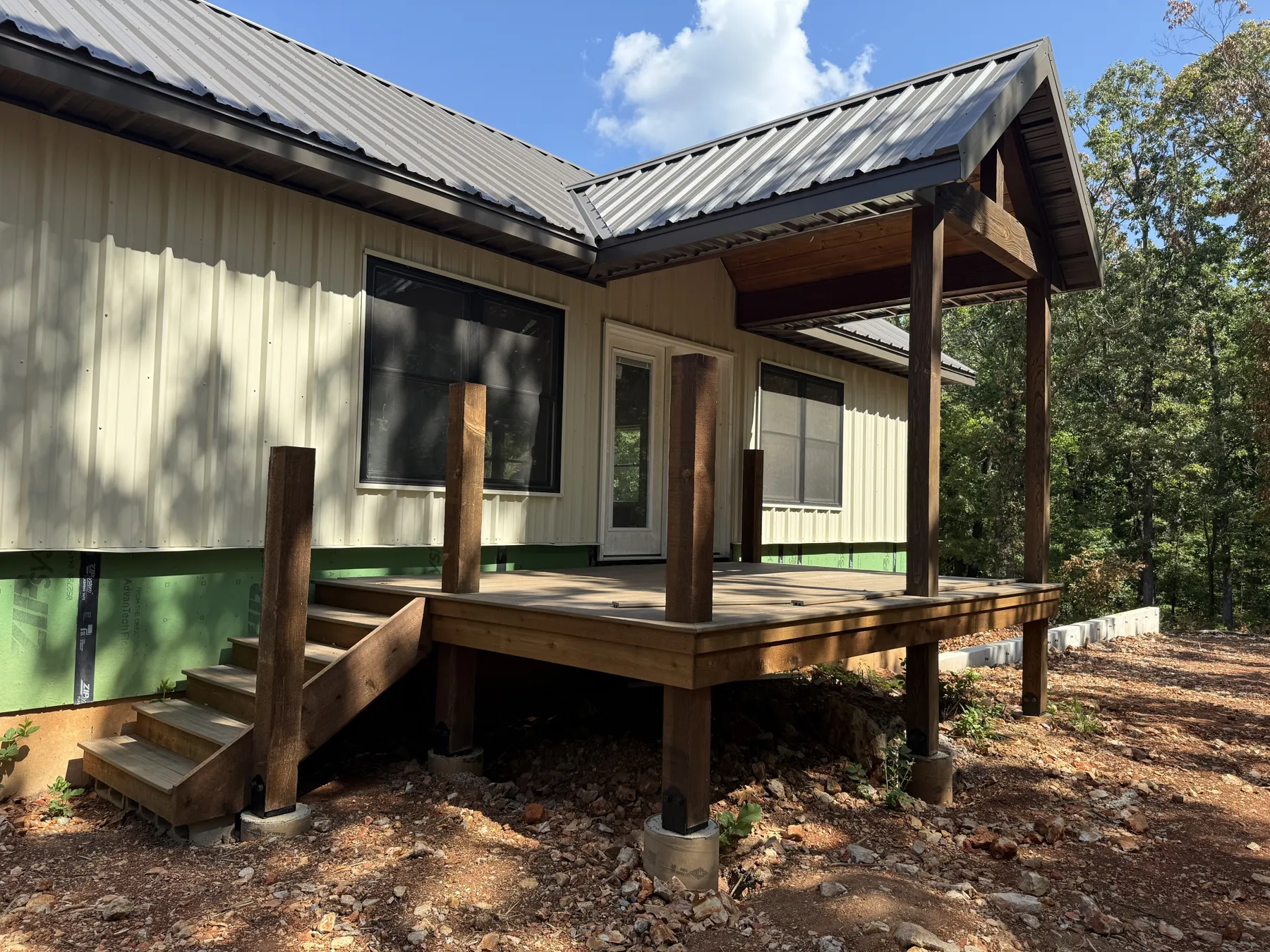 Covered side porch and stained wood deck on the pool house under construction